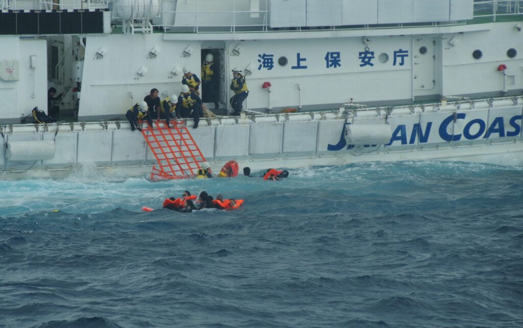 海上保安庁に救助される転覆した船の乗客ら＝16日、下地島沖（写真提供・第11管区海上保安本部）